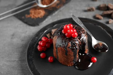 Photo of Delicious warm chocolate lava cake with berries on grey table, closeup