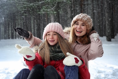 Mother and daughter having fun in forest on snow day