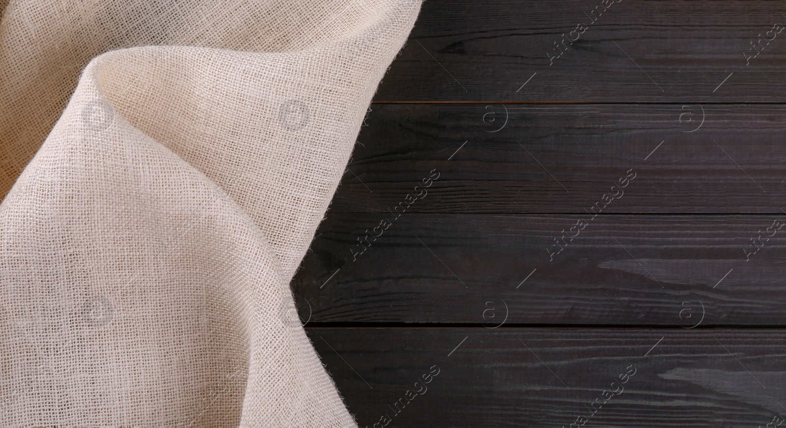 Photo of Beige burlap fabric on dark wooden table, top view. Space for text