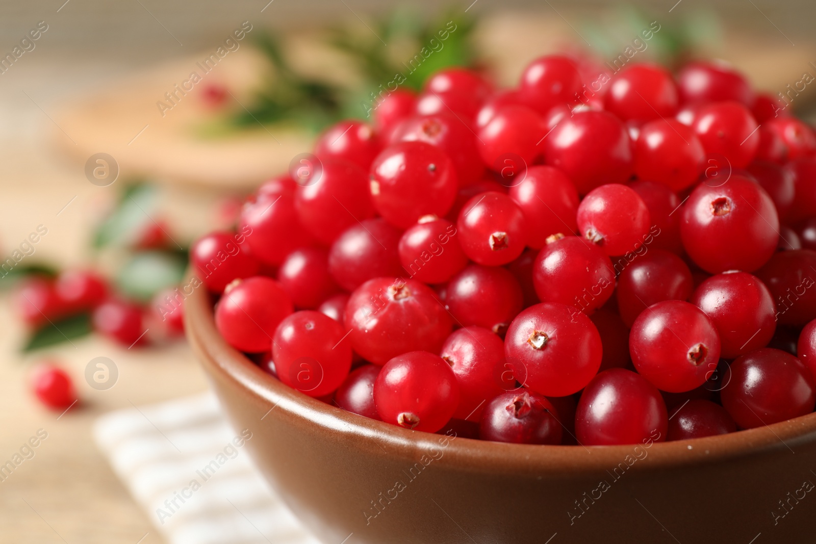 Photo of Bowl with tasty ripe cranberries on table, closeup