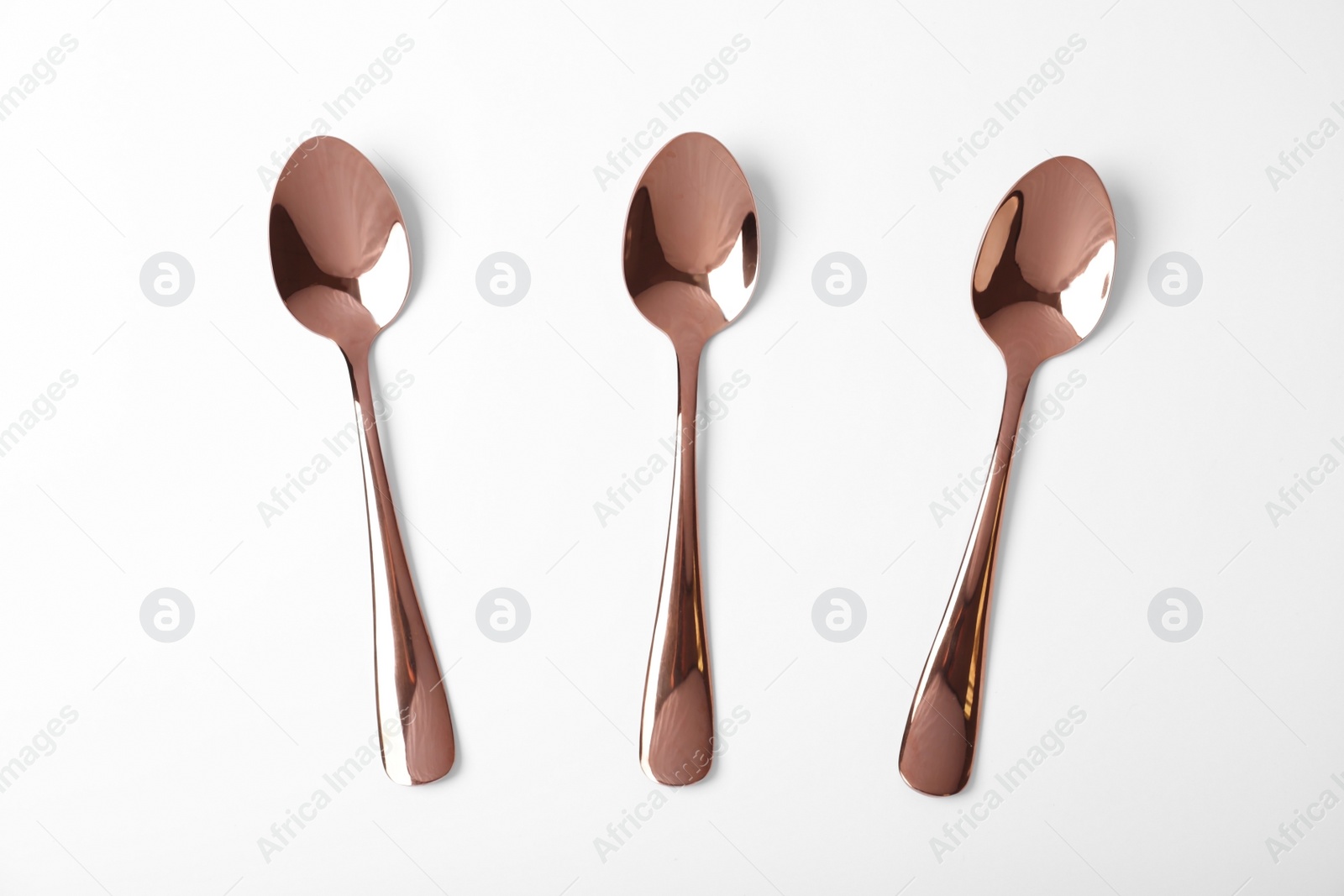 Photo of Set of new gold spoons on white background, top view