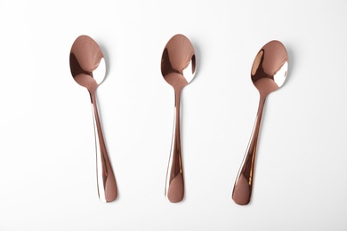 Set of new gold spoons on white background, top view