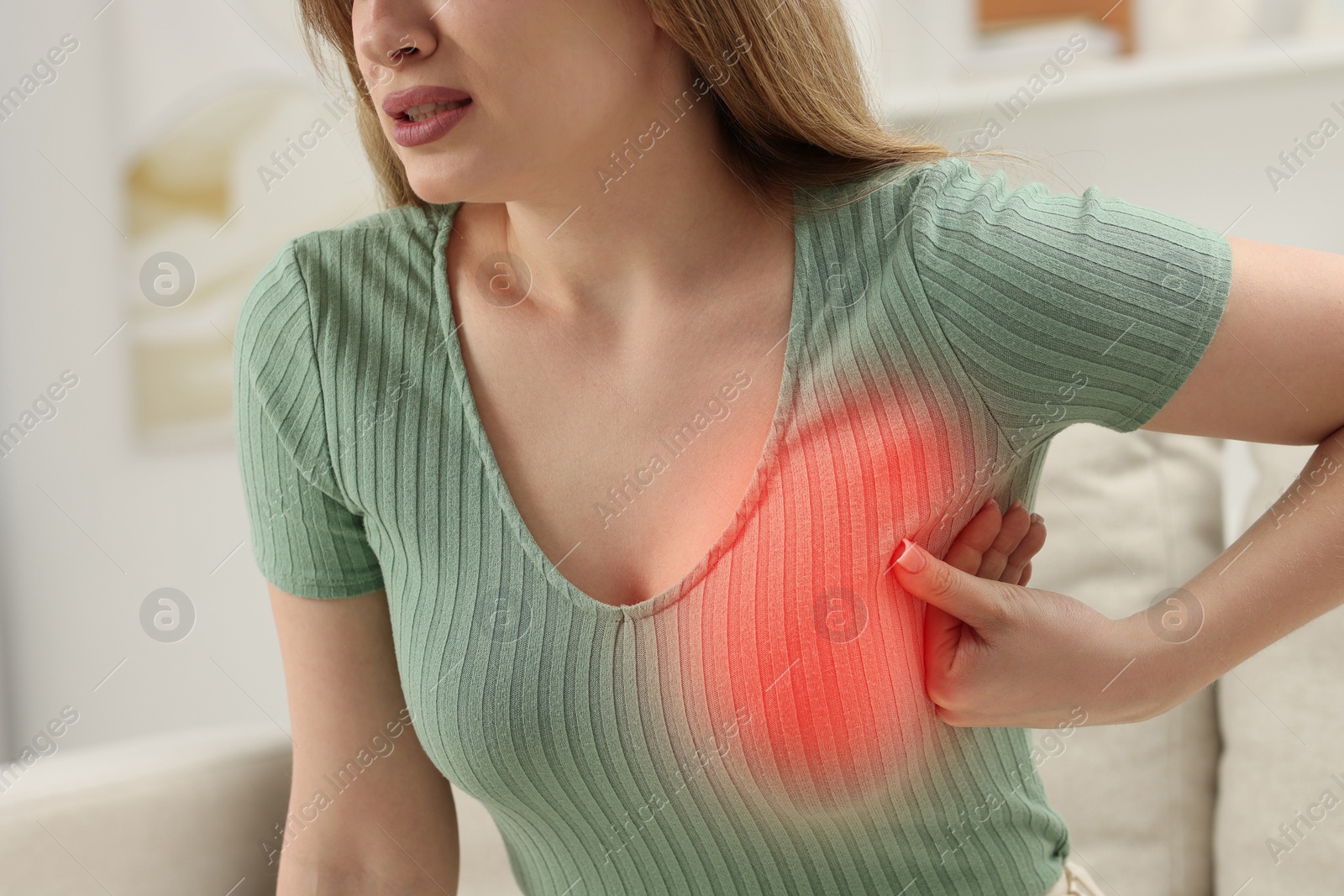 Image of Young woman suffering from breast pain at home, closeup