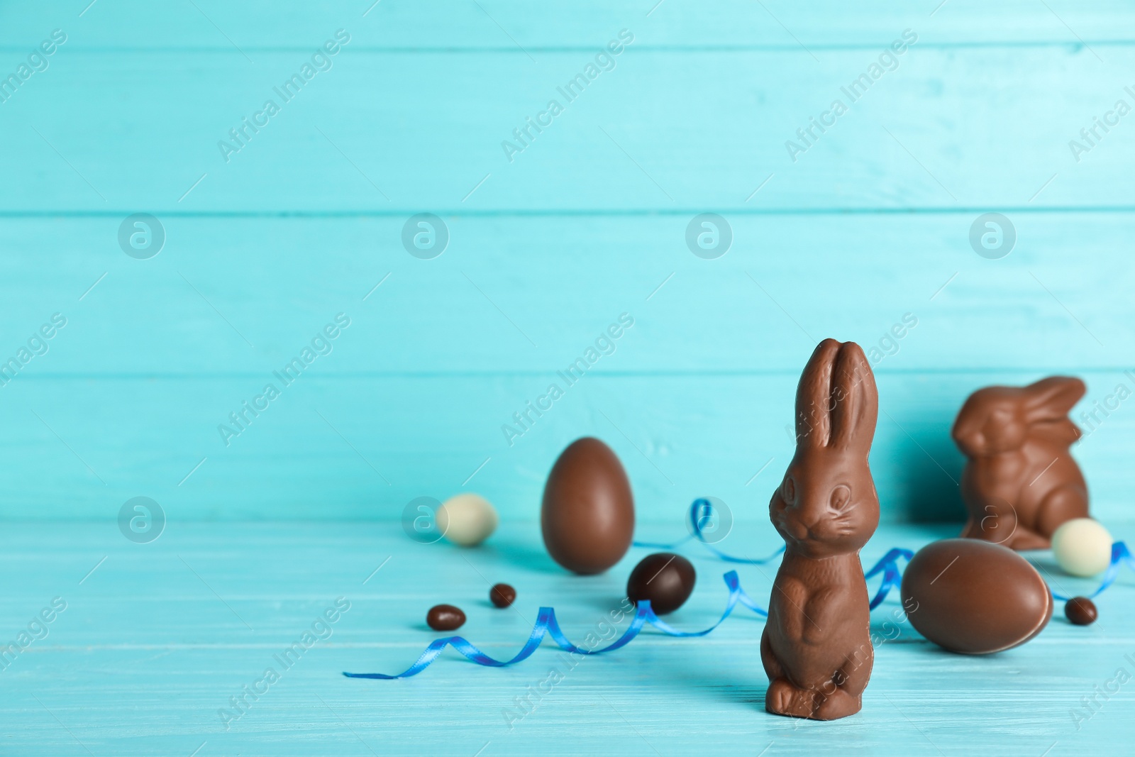 Photo of Composition with chocolate Easter eggs and bunny on table. Space for text