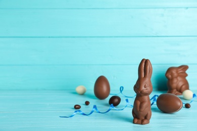 Photo of Composition with chocolate Easter eggs and bunny on table. Space for text