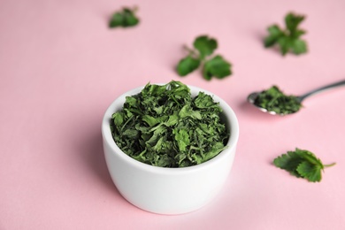 Bowl with dried parsley on pink background