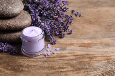 Stones, jar of cream and lavender flowers on wooden table. Space for text