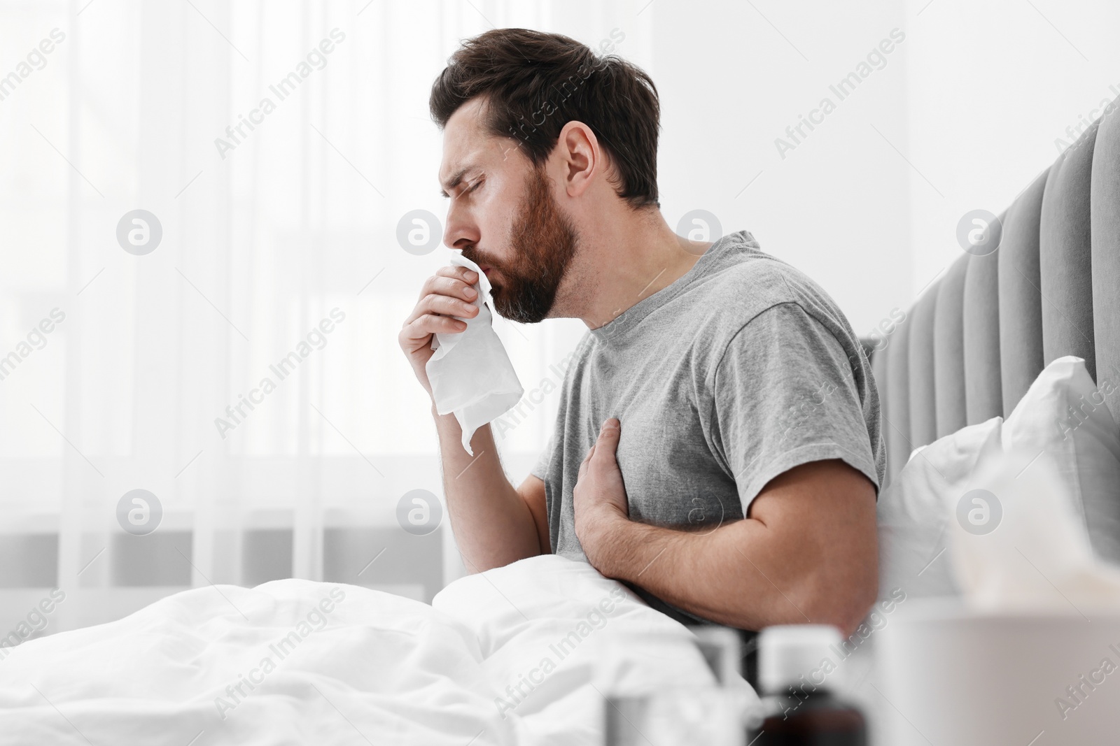 Photo of Sick man coughing on bed at home, space for text. Cold symptoms