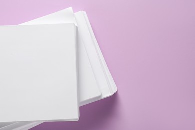 Photo of White paper sheets on violet background, top view. Space for text