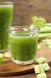 Glass of celery juice and fresh vegetable on wooden table, closeup