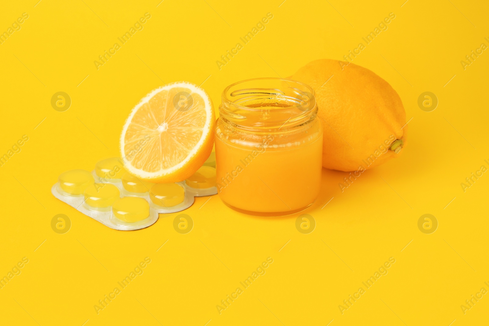 Photo of Cough drops, fresh lemons and honey on yellow background