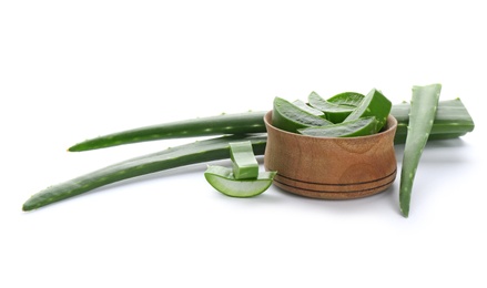 Photo of Bowl with pieces of aloe vera and green leaves on white background