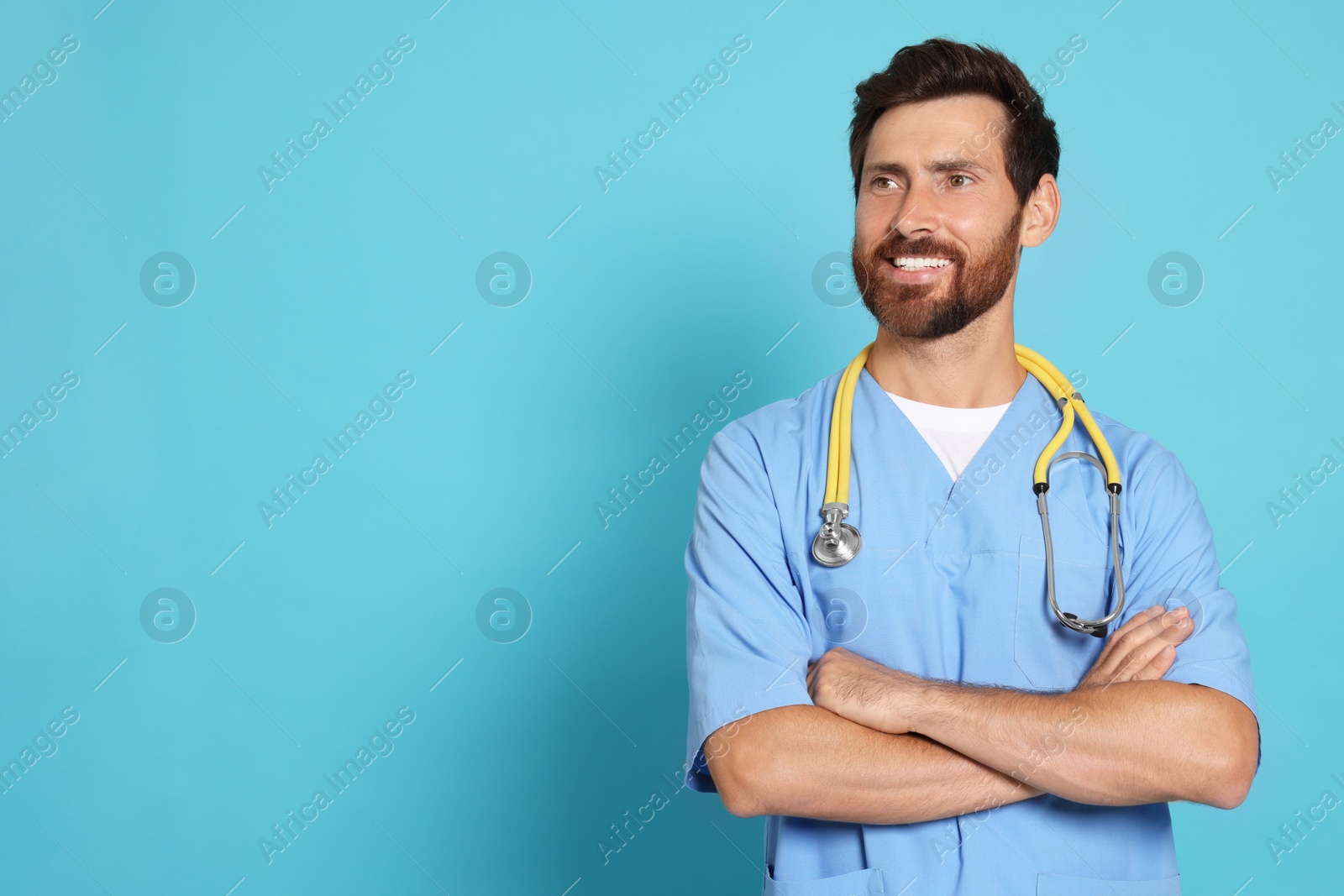 Photo of Happy doctor with stethoscope on light blue background. Space for text