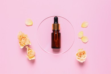 Photo of Bottle of cosmetic serum, flowers and petals on pink background, flat lay