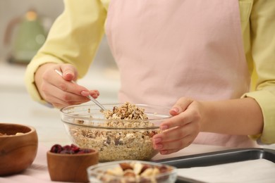 Woman making granola at table in kitchen, closeup