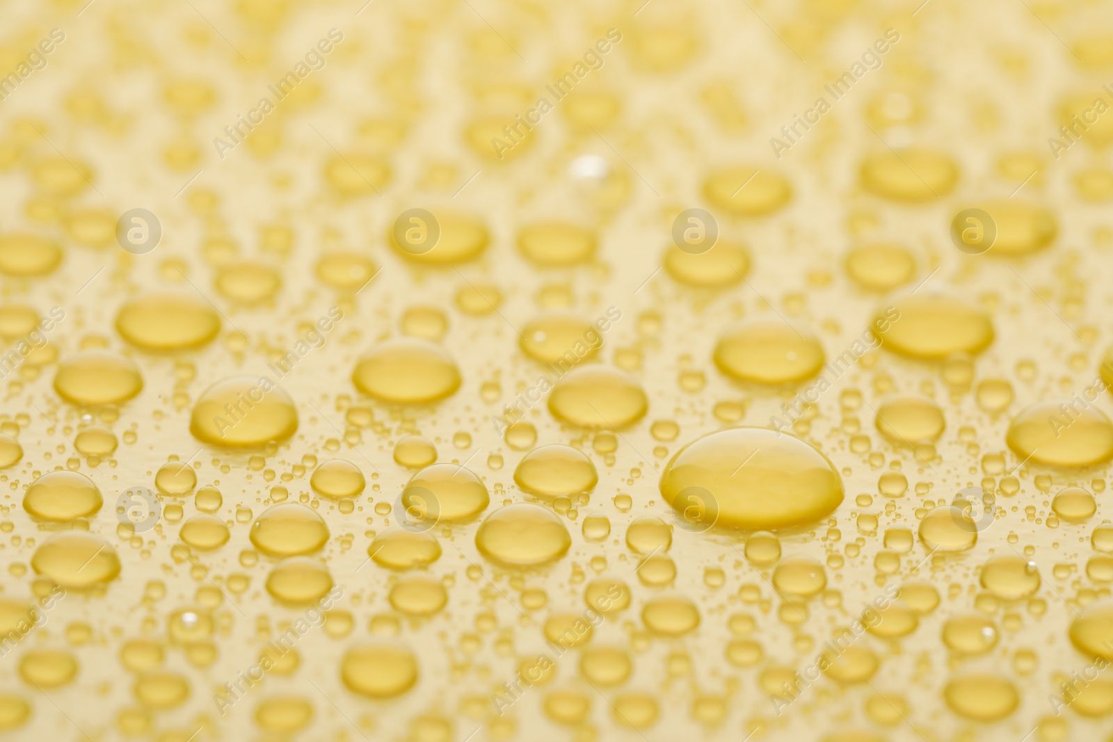 Photo of Water drops on yellow background, closeup view