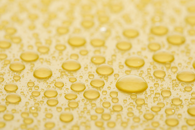 Photo of Water drops on yellow background, closeup view