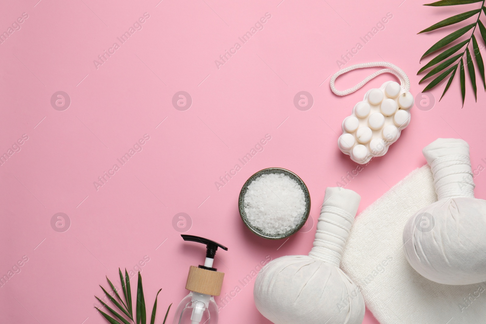 Photo of Beautiful spa composition with herbal massage bags and different care products on pink background, flat lay. Space for text