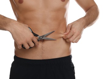 Fit man with scissors on white background, closeup. Weight loss surgery