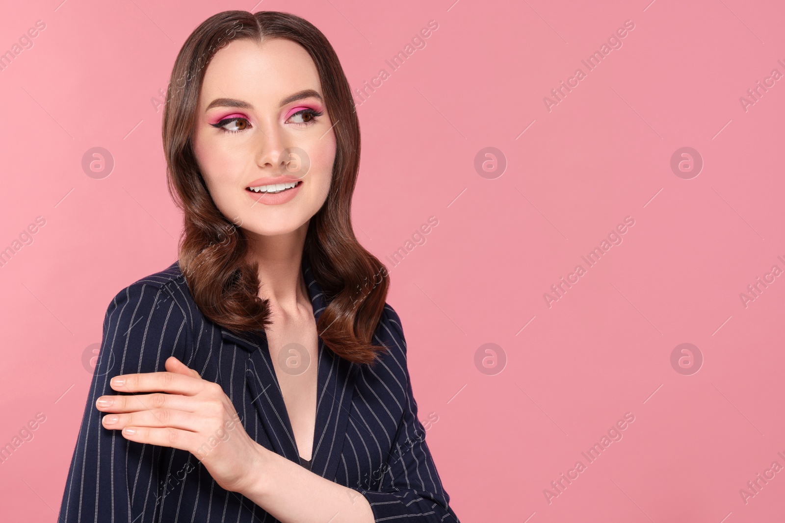 Photo of Portrait of beautiful young woman with makeup and gorgeous hair styling on pink background. Space for text