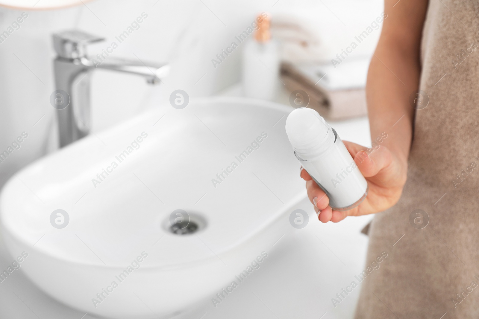 Photo of Young woman with roll on deodorant in bathroom, closeup view. Space for text