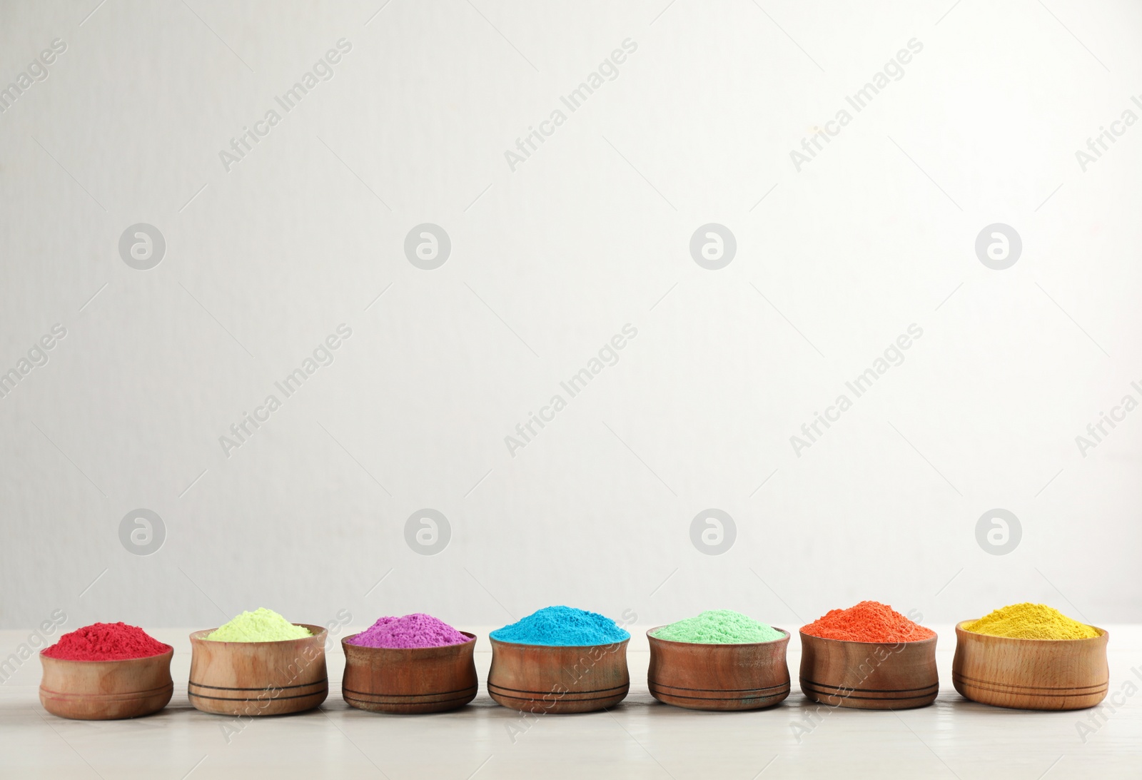 Photo of Colorful powder dyes on white wooden background, space for text. Holi festival