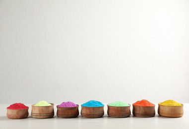 Colorful powder dyes on white wooden background, space for text. Holi festival
