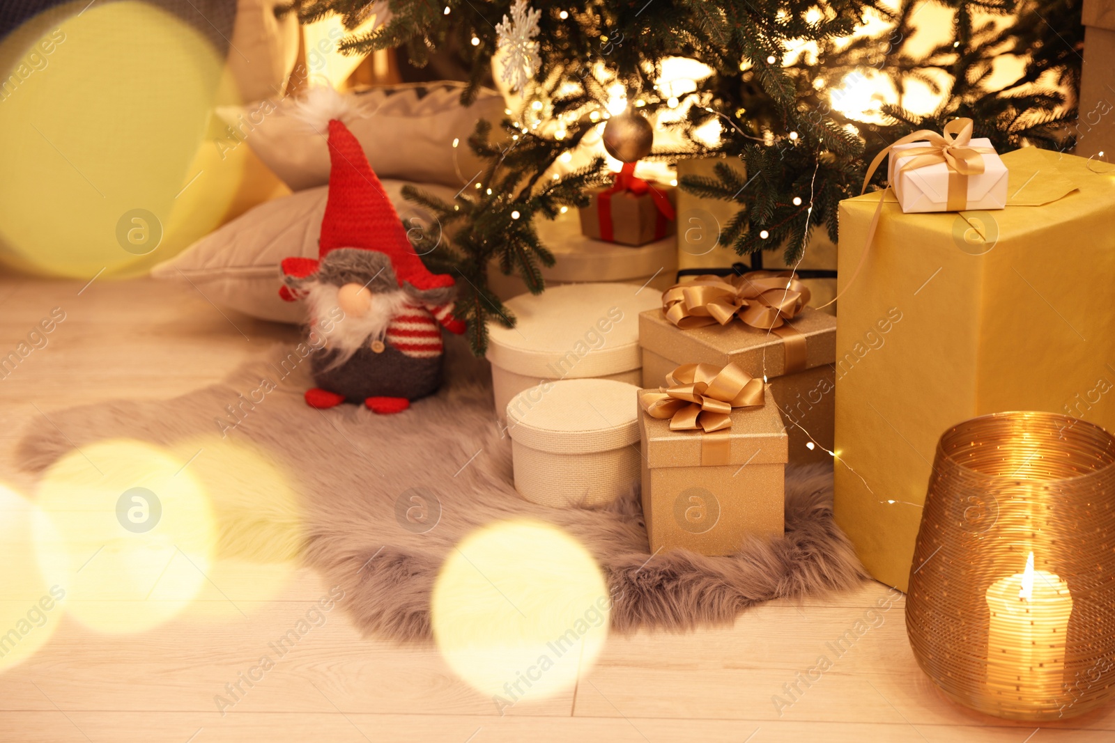 Photo of Christmas tree, gift boxes and gnome indoors. Bokeh effect