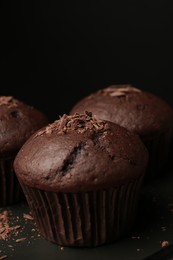 Photo of Delicious cupcakes with chocolate crumbles on black table, closeup