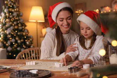 Photo of Mother with her cute little daughter making Christmas cookies in kitchen