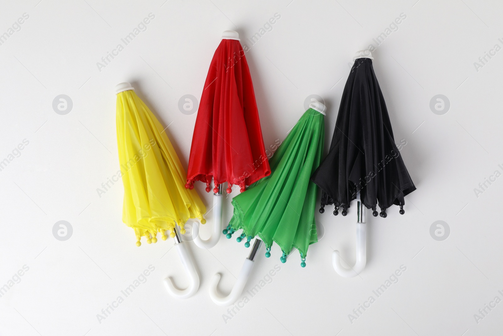 Photo of Small color umbrellas on white background, top view