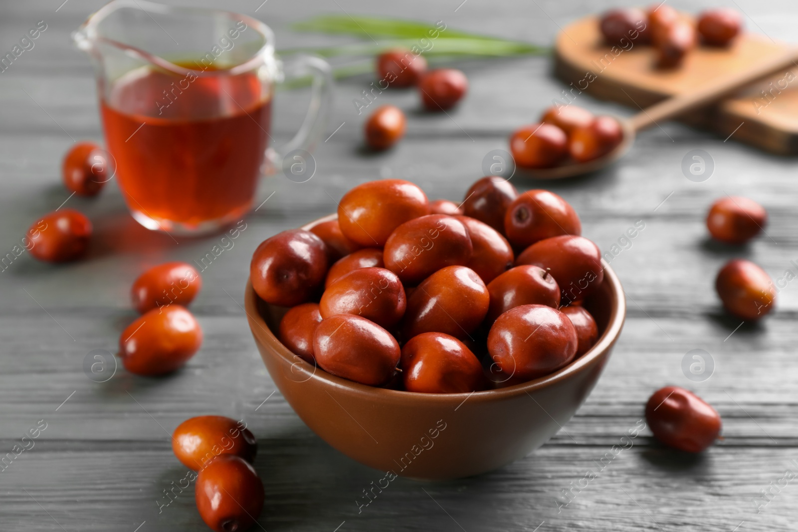 Photo of Palm oil fruits in bowl on grey wooden table, closeup