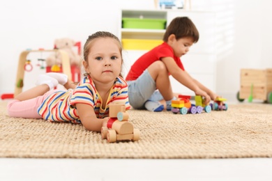 Cute little children playing with toys on floor at home