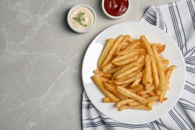 Photo of Tasty french fries served on grey marble table, flat lay. Space for text