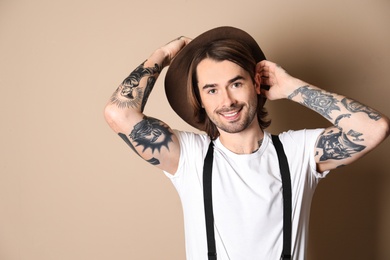 Photo of Young man with tattoos on arms against beige background