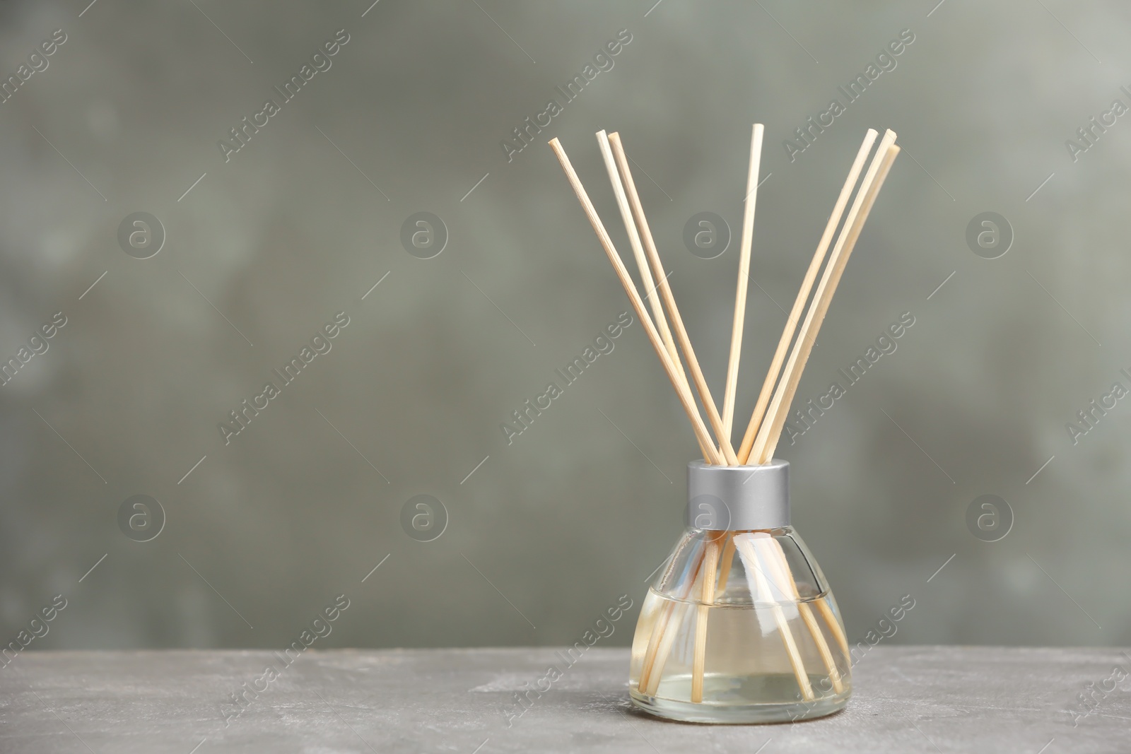 Photo of Aromatic reed freshener on table against grey background