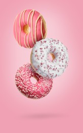 Image of Sweet tasty donuts falling on pink background