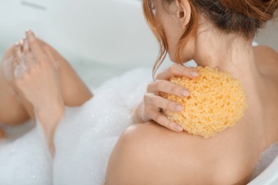 Woman with sponge taking bubble bath, closeup