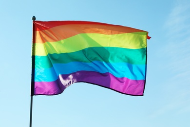 Photo of Rainbow gay flag against blue sky. LGBT concept