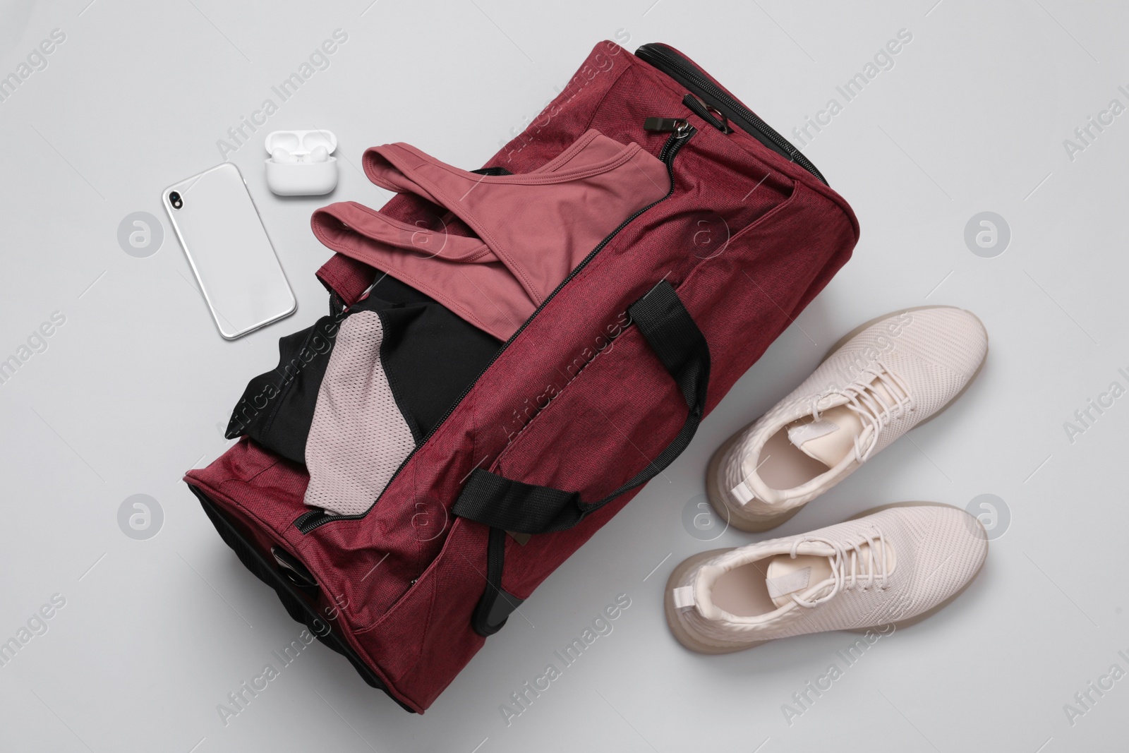 Photo of Gym bag and sports equipment on light grey background, flat lay