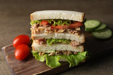 Delicious sandwich with tuna, tomatoes and lettuce on wooden table, closeup