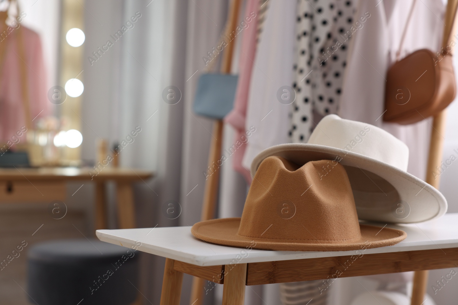 Photo of Stylish hats on white wooden table in makeup room