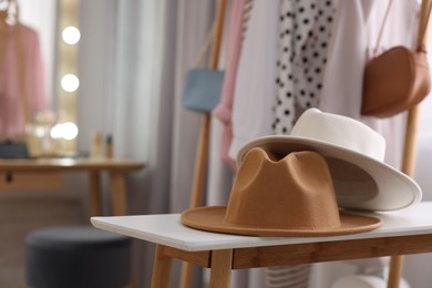 Photo of Stylish hats on white wooden table in makeup room
