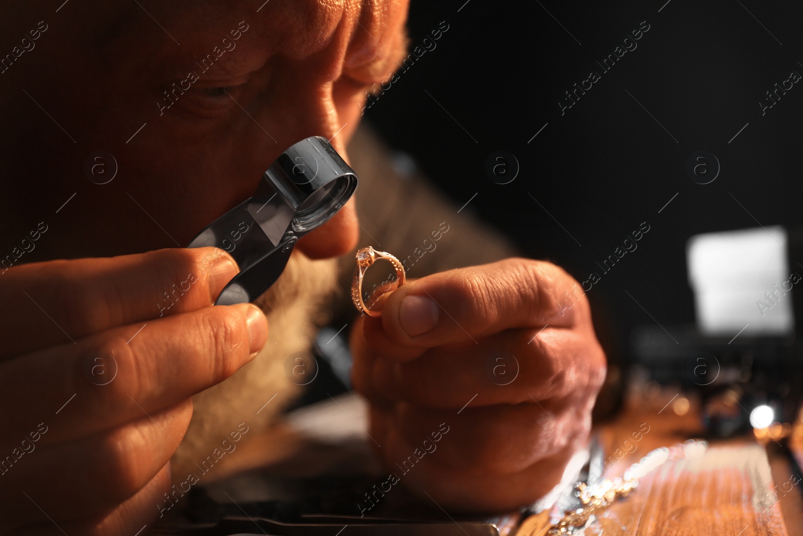 Photo of Male jeweler evaluating diamond ring in workshop, closeup view