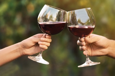 Couple with glasses of red wine outdoors, closeup