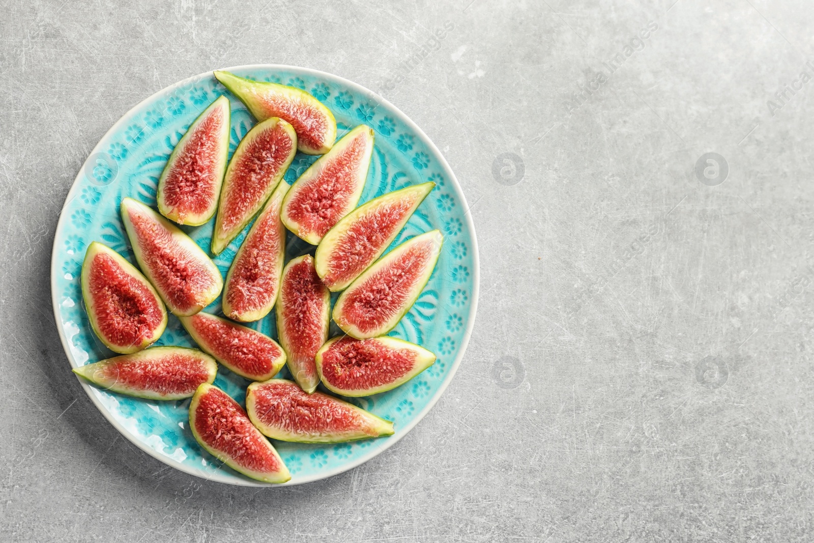 Photo of Plate with fresh ripe fig slices on gray background, top view. Space for text