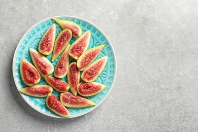 Photo of Plate with fresh ripe fig slices on gray background, top view. Space for text