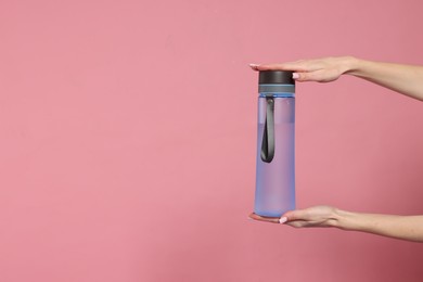 Photo of Woman holding transparent bottle on pink background, closeup. Space for text