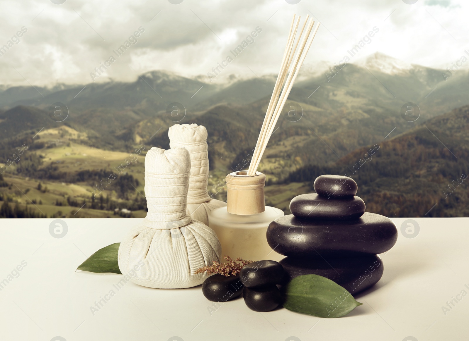 Image of Beautiful composition with spa stones white table against mountain landscape