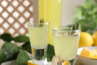 Photo of Tasty limoncello liqueur with rosemary on table, closeup. Space for text